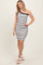 woman wearing a black and white striped one-shoulder bodycon dress and white strappy sandals