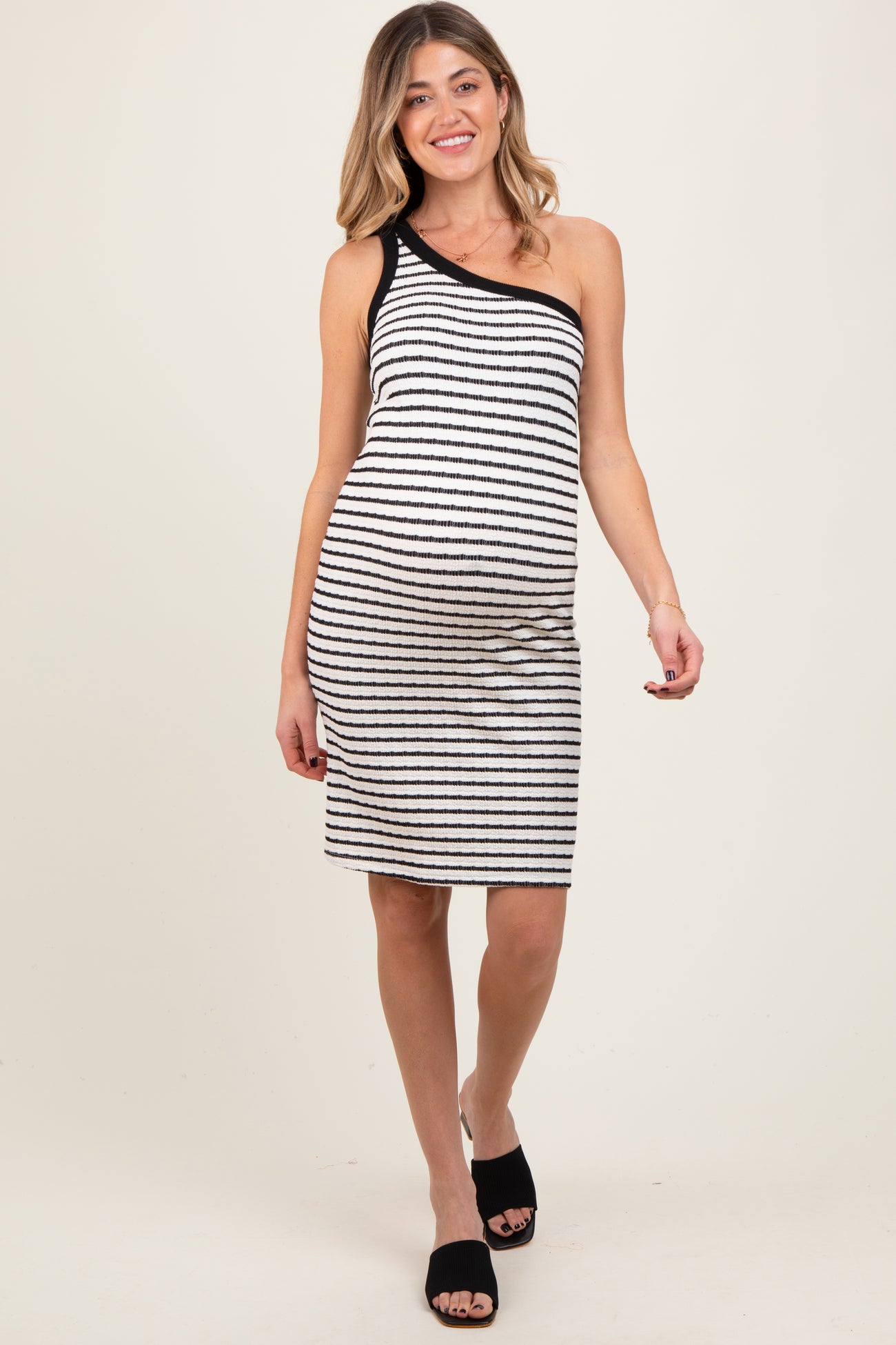 woman wearing a black and white striped maternity dress with one shoulder and a visible baby bump