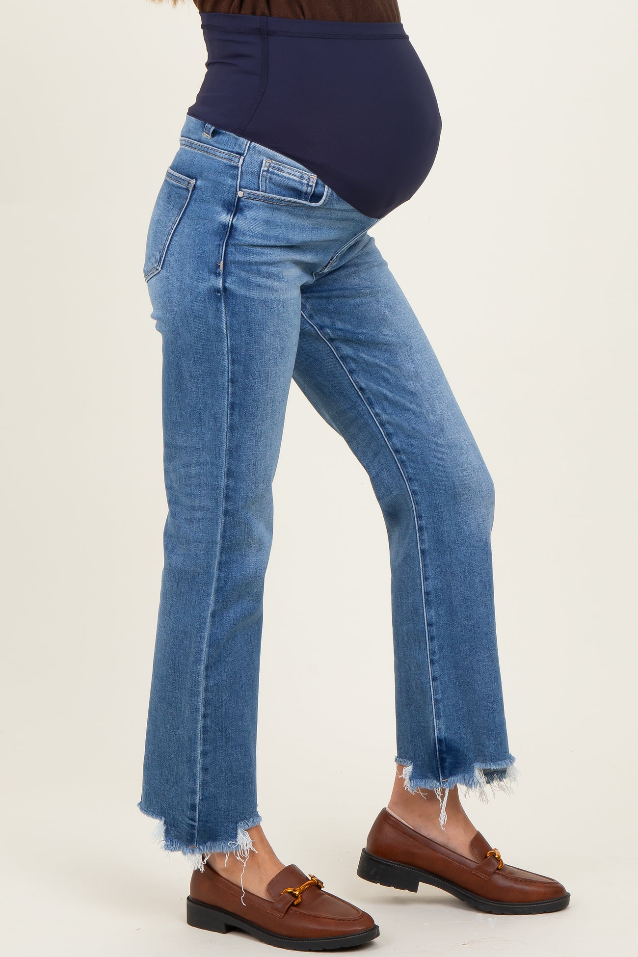 woman wearing blue flared maternity jeans with a raw hem and a visible baby bump