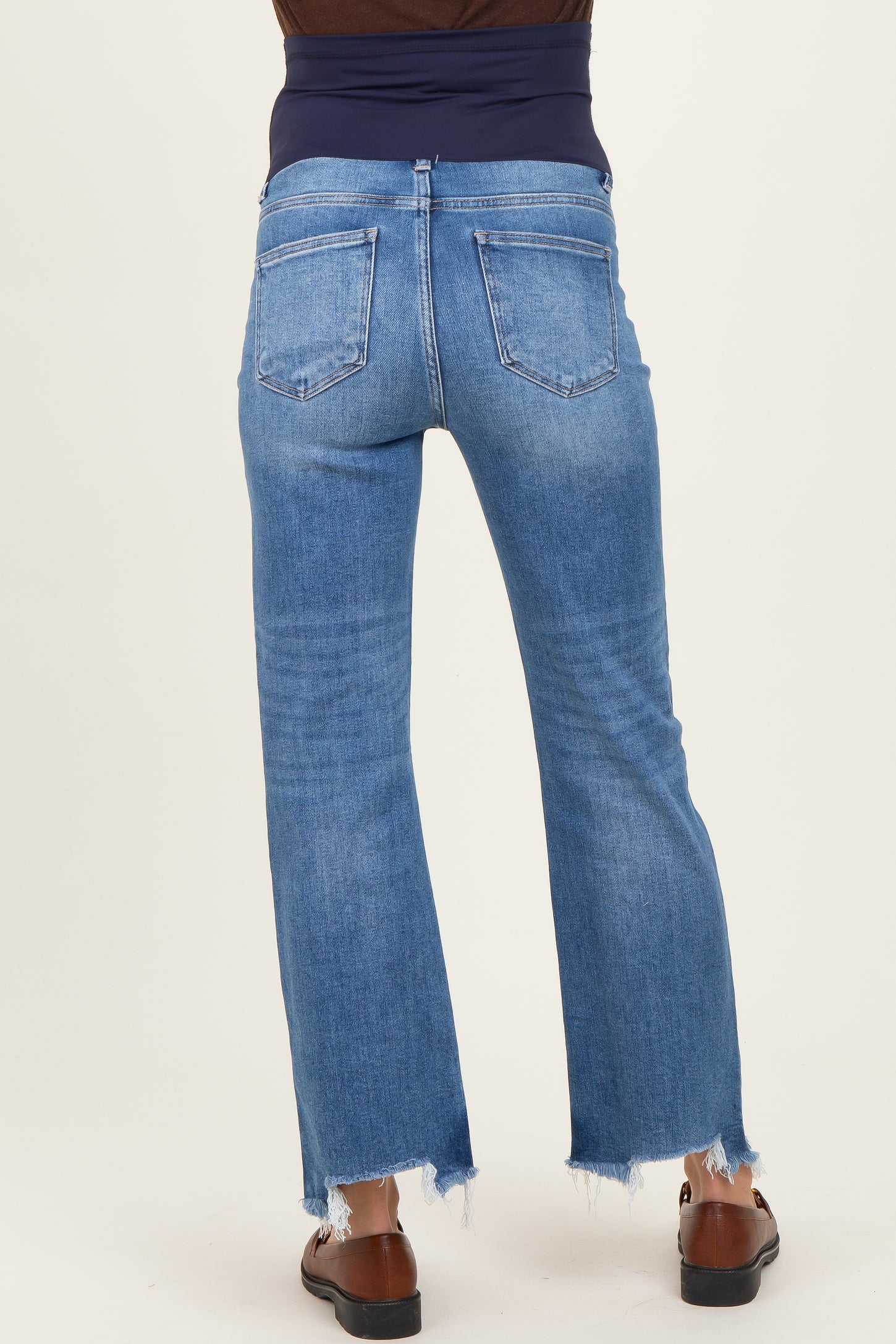 woman wearing blue maternity jeans with a distressed hem and a dark waistband, showing the back view