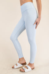 woman wearing light blue ribbed high-waisted leggings and white slide sandals