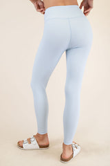 woman wearing light blue ribbed leggings and white slide sandals, viewed from the back