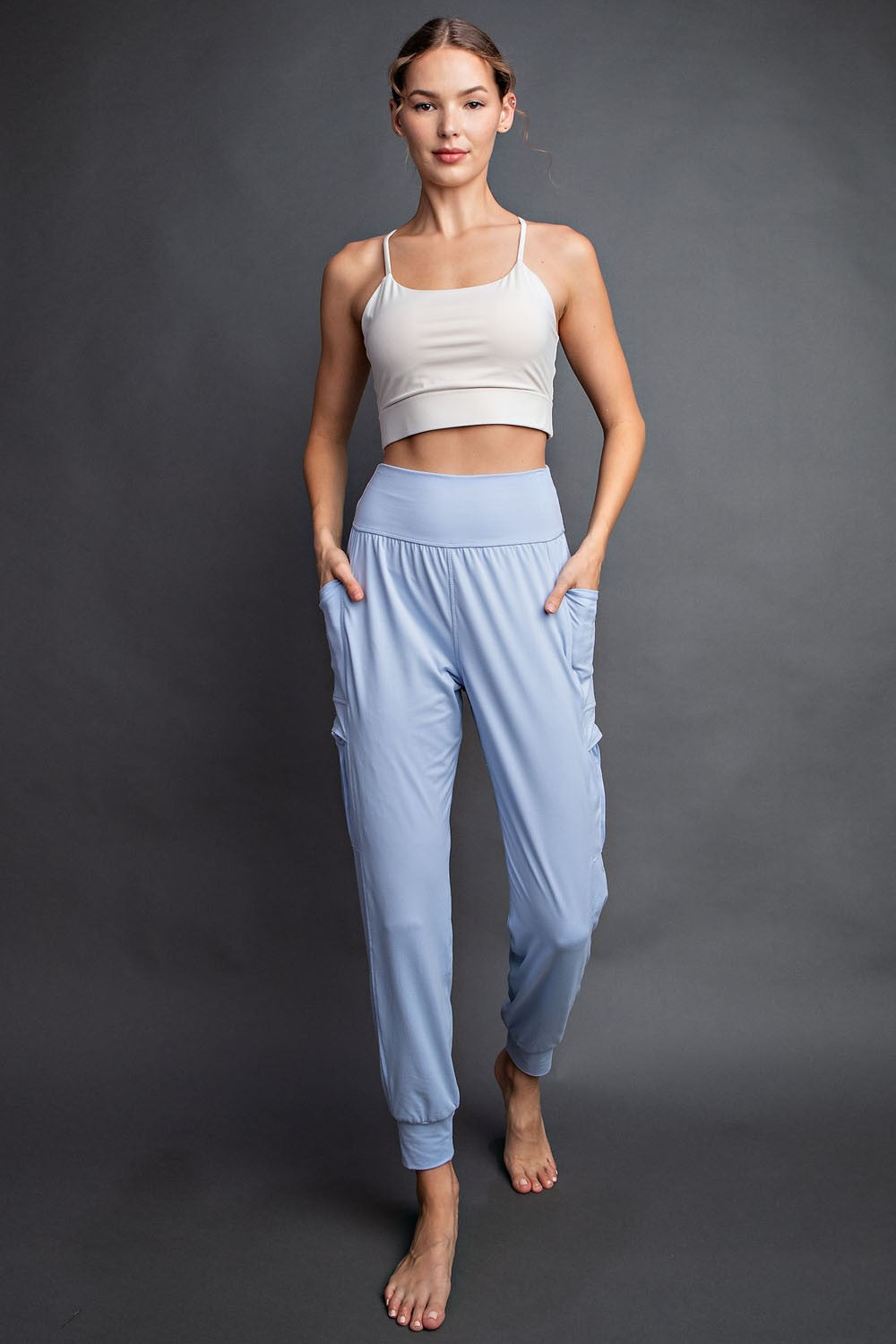 woman wearing a beige cropped tank top and light blue jogger pants with side pockets
