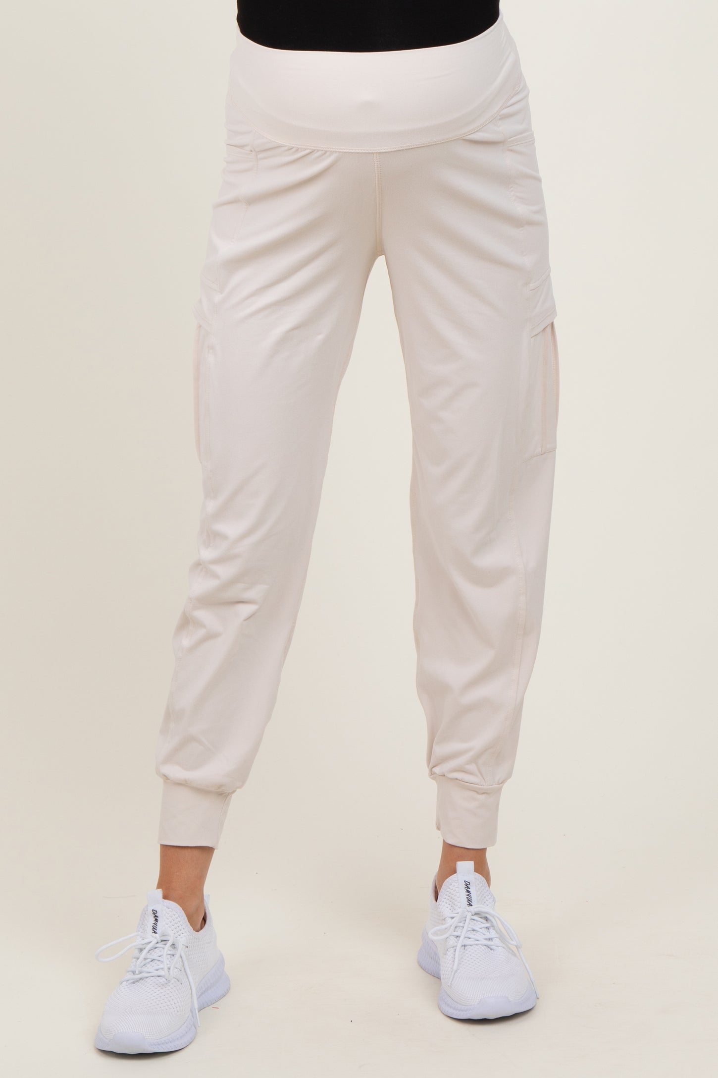 woman wearing light beige maternity joggers with side pockets and a stretchy waistband