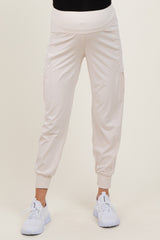 woman wearing light beige maternity joggers with side pockets and a stretchy waistband