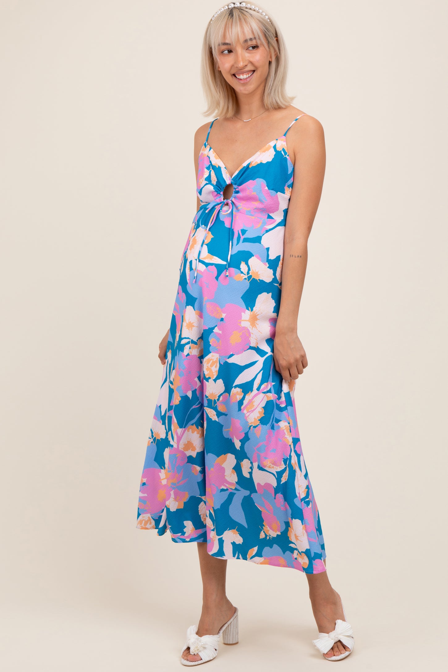 woman wearing a blue floral maternity dress with a tie waist and a flowing skirt, showing her baby bump