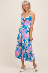 woman wearing a blue floral maternity dress with a tie waist and a flowing skirt, showing her baby bump