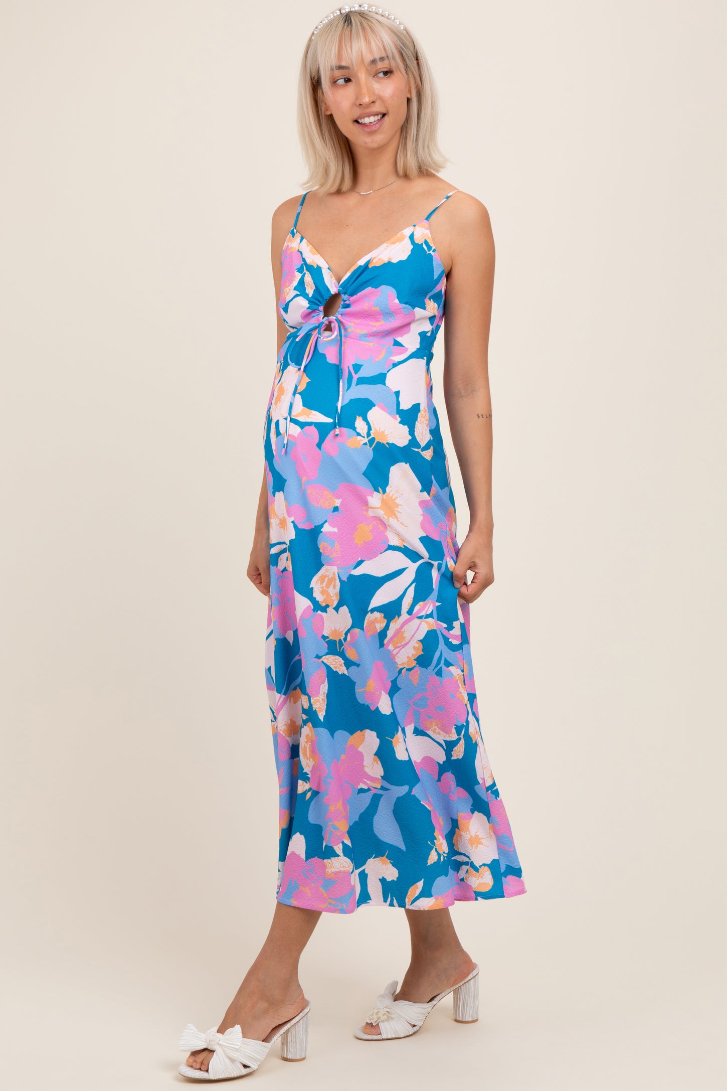 woman wearing a blue floral maternity dress with a knot detail and a visible baby bump