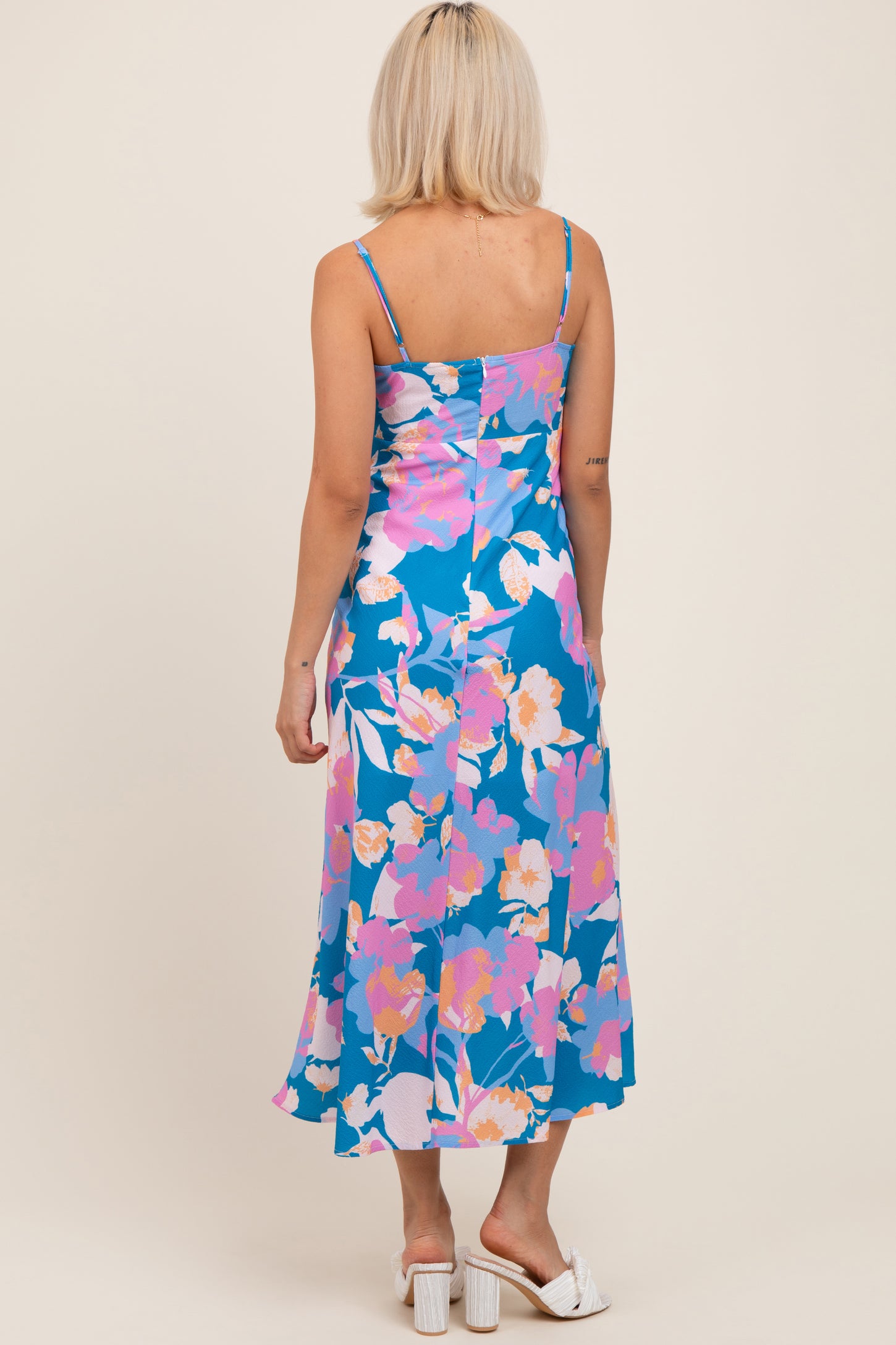 woman wearing a blue floral maternity dress with adjustable straps, showing the back view