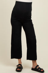 woman wearing black maternity jeans with a wide leg and over-the-bump panel, paired with black sandals