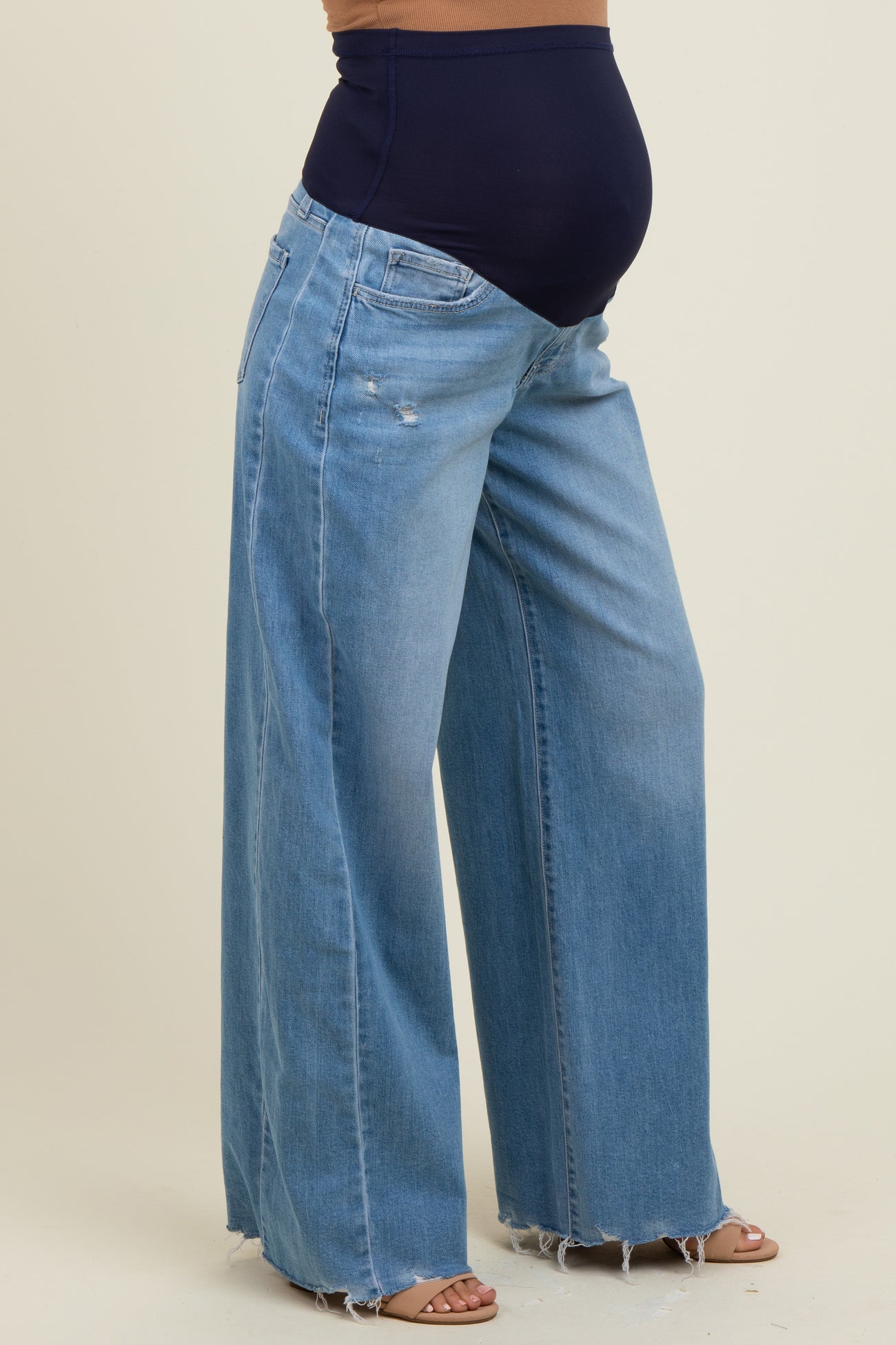 woman wearing light blue maternity wide-leg jeans with a navy belly panel and a visible baby bump