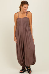 woman wearing a brown sleeveless jumpsuit with smocked bodice and wide leg design