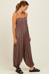 woman wearing a brown sleeveless jumpsuit with a smocked bodice and wide legs, styled with black sandals
