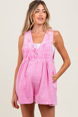 woman wearing a pink maternity romper with pleats and side pockets, and a loose fit around the baby bump