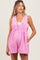 woman wearing a pink maternity romper with pleats and side pockets, and a loose fit around the baby bump