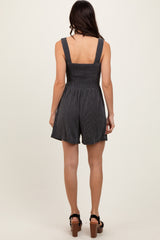 woman wearing a black and white striped smocked romper with a fitted bodice and flared shorts, viewed from the back