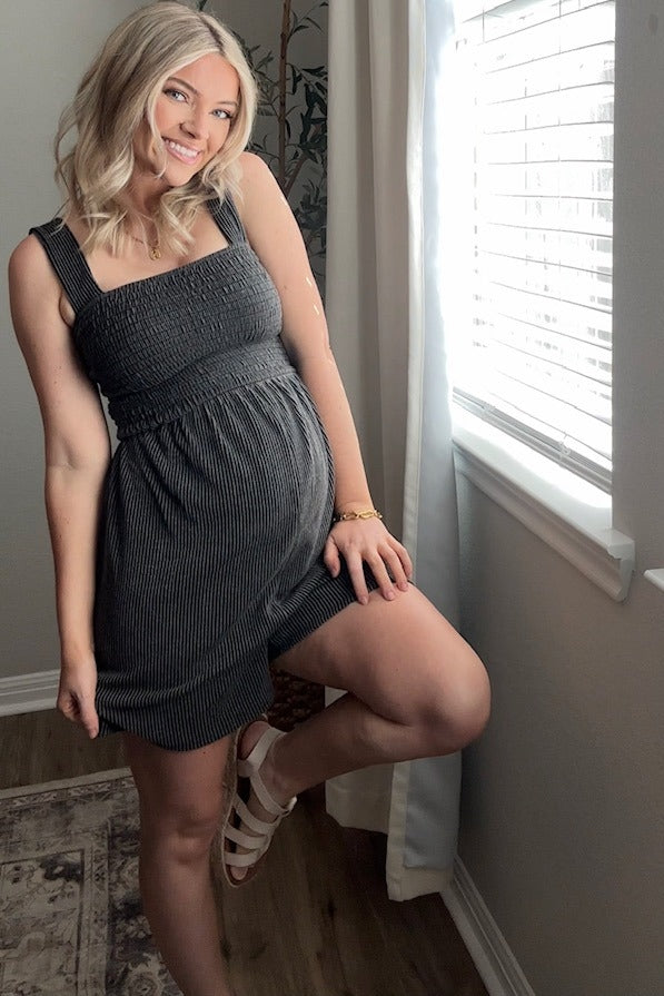 woman wearing a gray ribbed maternity dress with a fitted bodice and flowing skirt, showing her baby bump