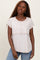 woman wearing a light beige short sleeve top with a layered design and relaxed fit, paired with blue jeans