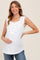 woman wearing a white sleeveless maternity top with button details and holding her baby bump