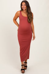 woman wearing a rust colored fitted maternity maxi dress with a visible baby bump