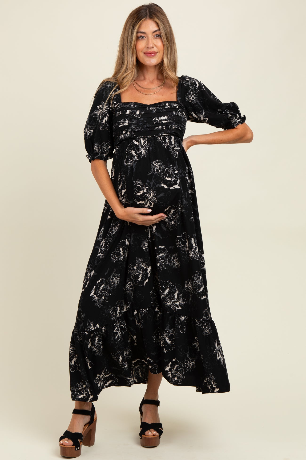woman wearing a black floral maternity maxi dress and holding her baby bump