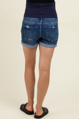 woman wearing dark denim maternity shorts with a stretchy waistband and frayed hem, showing a casual style.