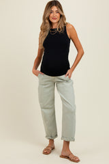 woman wearing a black sleeveless maternity top and light green baggy maternity jeans, showing a baby bump