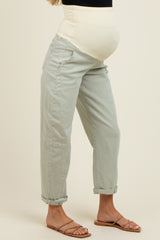 woman wearing light green maternity pants with a white belly panel and rolled cuffs, showcasing a visible baby bump