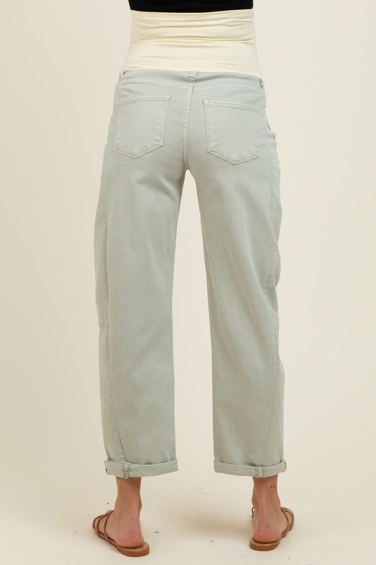 woman wearing light green maternity pants with a rolled cuff and a wide waistband, showing a relaxed fit from the back