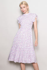 woman wearing a light purple floral midi dress with ruffle sleeves and a tiered skirt