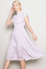 woman wearing a lavender floral print midi dress with ruffled sleeves and a smocked waist