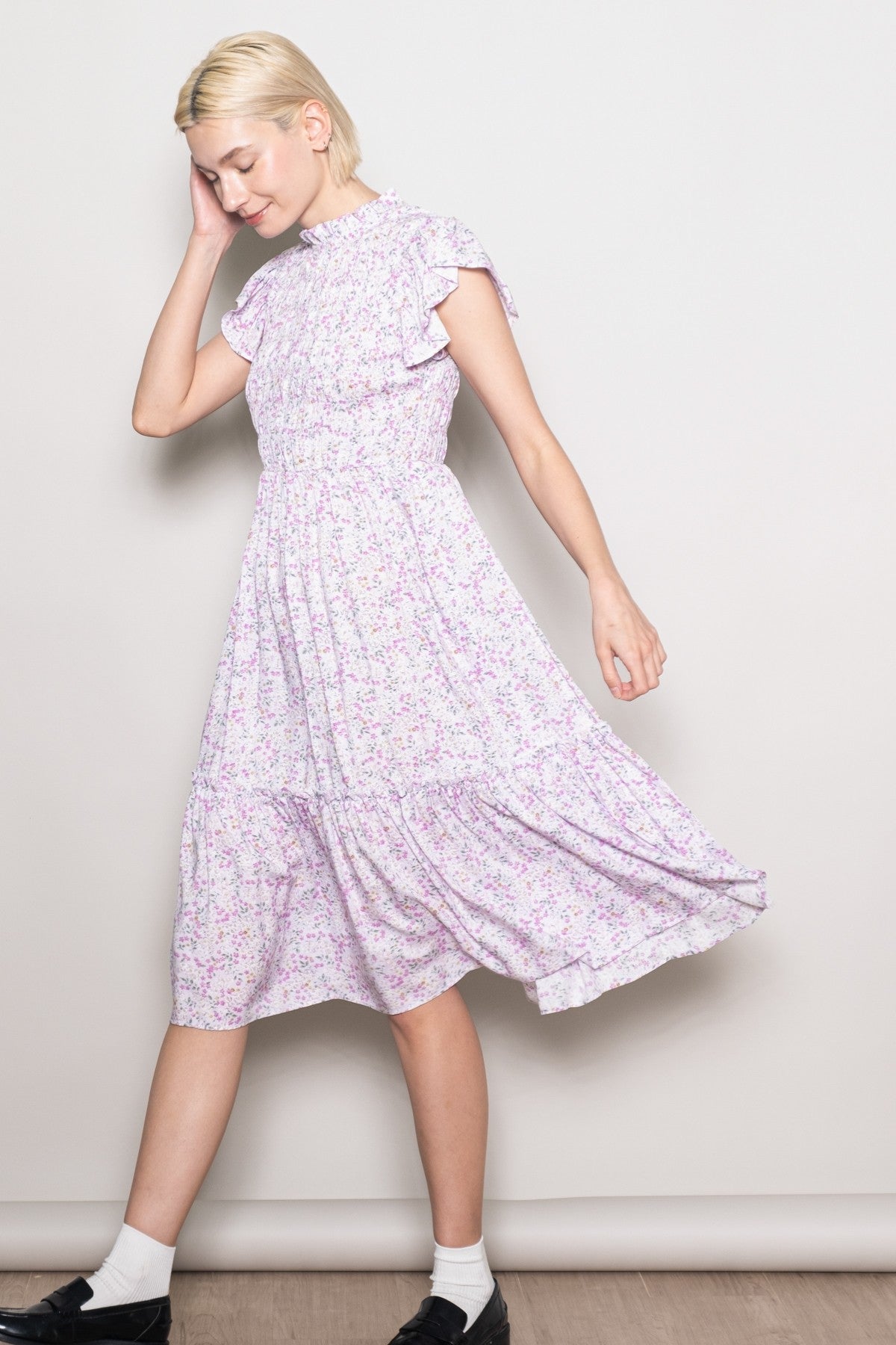 woman wearing a lavender floral midi dress with ruffle sleeves and a tiered skirt