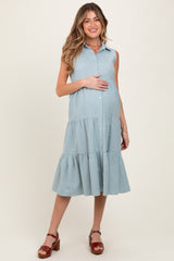 woman wearing a light blue sleeveless maternity dress with tiered ruffle details and holding her baby bump