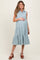 woman wearing a light blue sleeveless maternity dress with tiered ruffle details and holding her baby bump