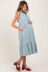 woman wearing a light blue sleeveless maternity dress with pockets and tiered skirt, showing baby bump