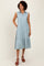 woman wearing a light blue sleeveless button-up midi dress with tiered layers and side pockets