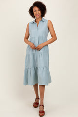 woman wearing a light blue sleeveless button-up tiered dress with a collared neckline and a flowy silhouette
