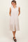 woman wearing a beige sleeveless button-up tiered midi dress with side pockets and black platform heels
