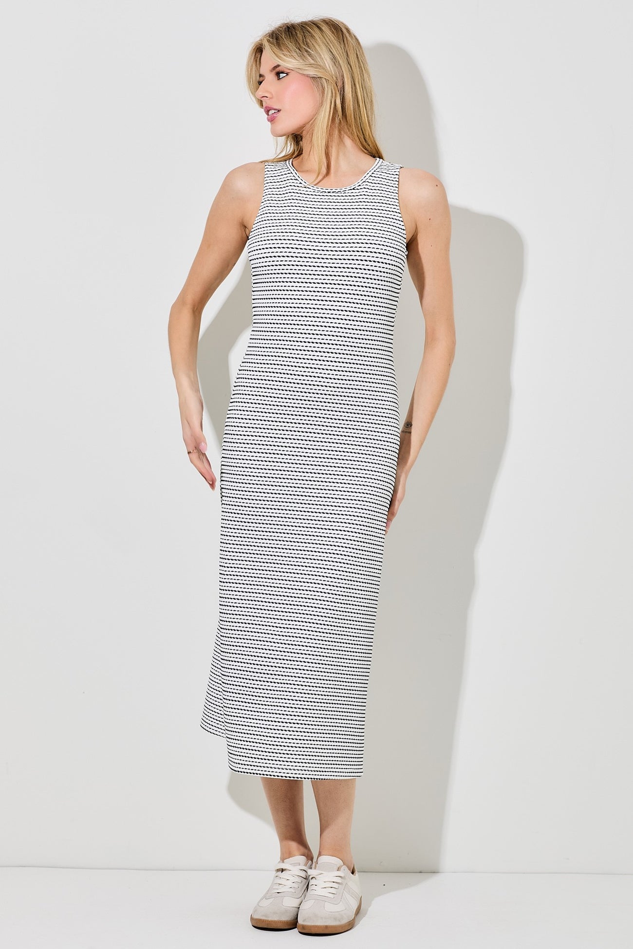 woman wearing a sleeveless black and white striped midi dress with a relaxed fit and sneakers