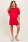 woman wearing a bright red maternity dress with short sleeves and a baby bump visible, styled with white sandals