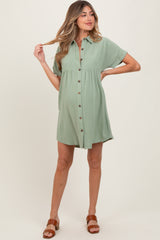 woman wearing a sage green short sleeve maternity dress with buttons and a gathered waist, showing her baby bump
