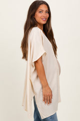 woman wearing a cream maternity kimono with crochet trim and a visible baby bump, styled with blue jeans