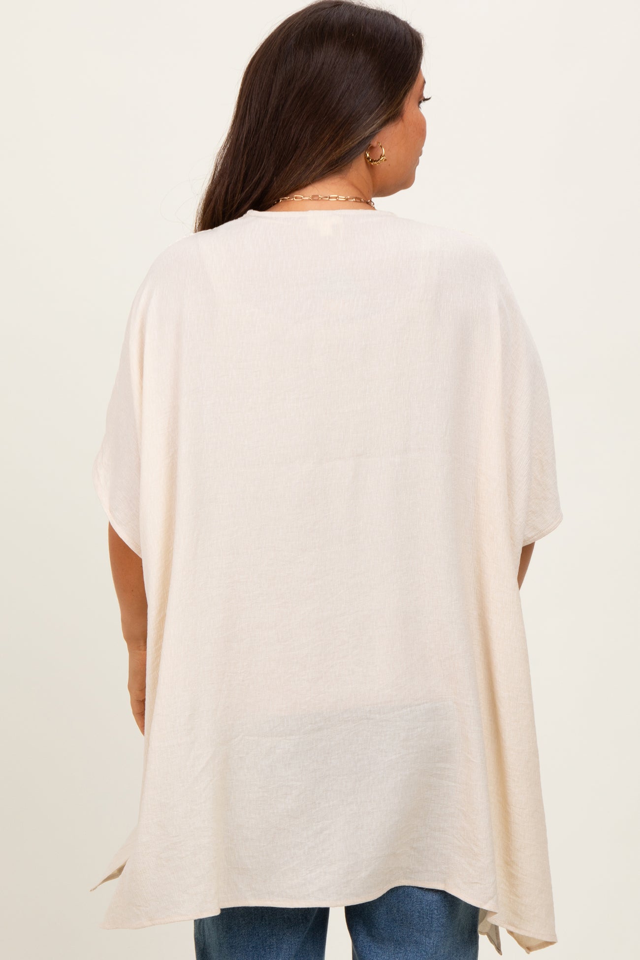woman wearing a light beige maternity top with a loose fit and short sleeves, shown from the back