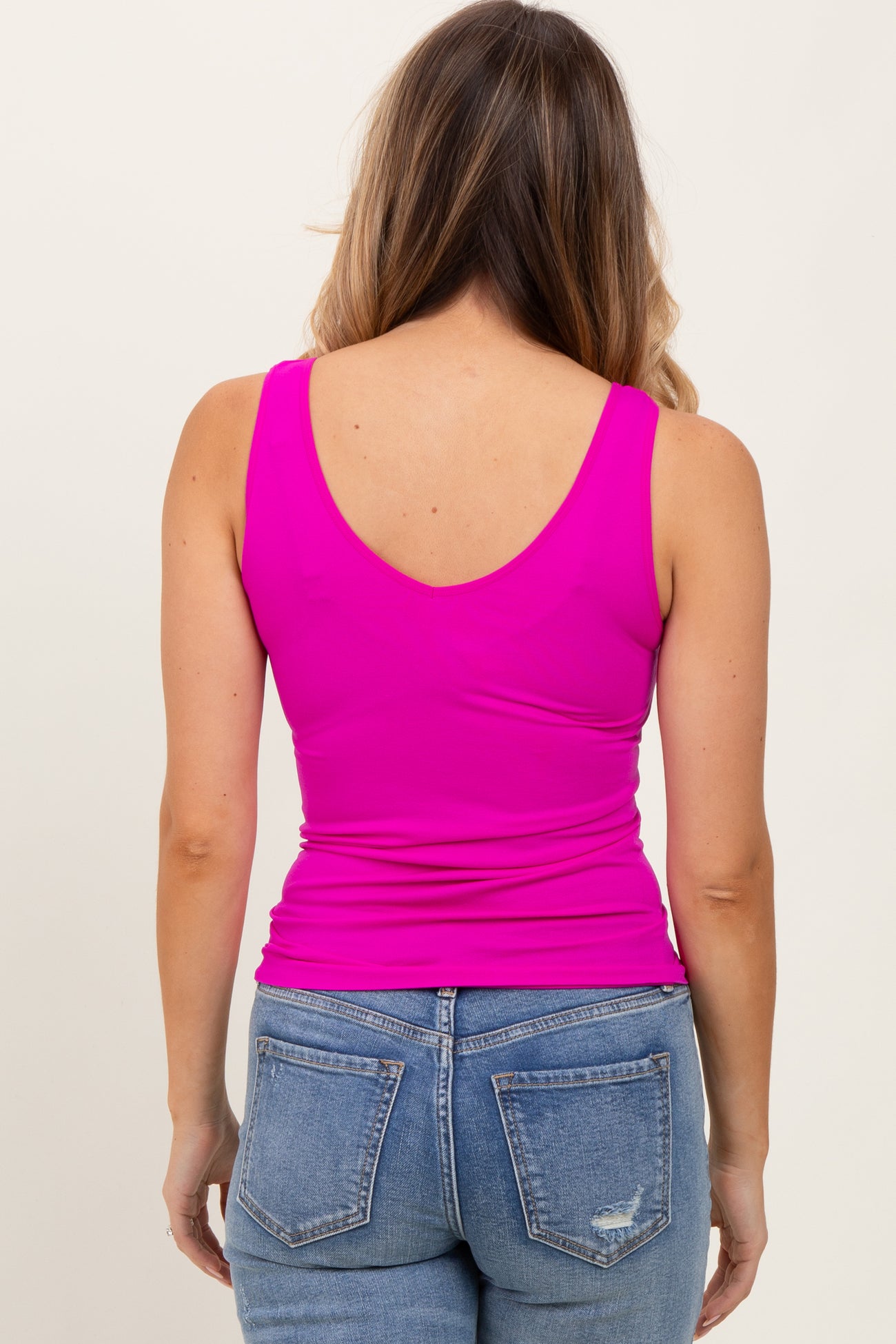 woman wearing a fuchsia sleeveless top and blue jeans, view from the back