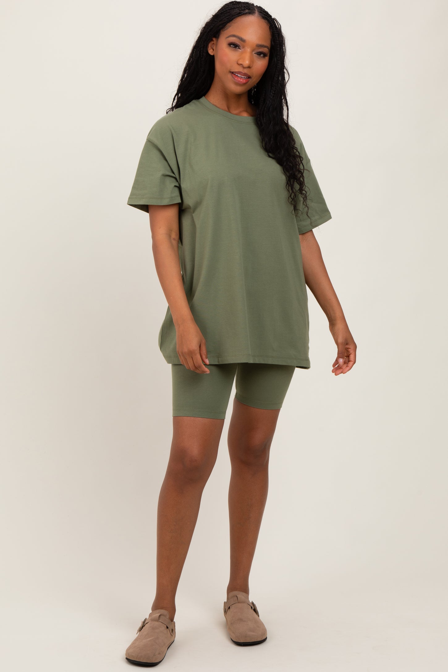 woman wearing an oversized olive green t-shirt with matching bike shorts and tan slip-on shoes