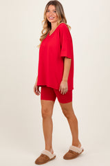 woman wearing a red oversized v-neck t-shirt and red bike shorts, paired with tan slippers