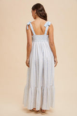 woman wearing a light blue and white floral maxi dress with tie straps and smocked back detail