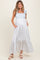 woman wearing a blue and white floral maternity maxi dress with tie straps and pockets, featuring a baby bump