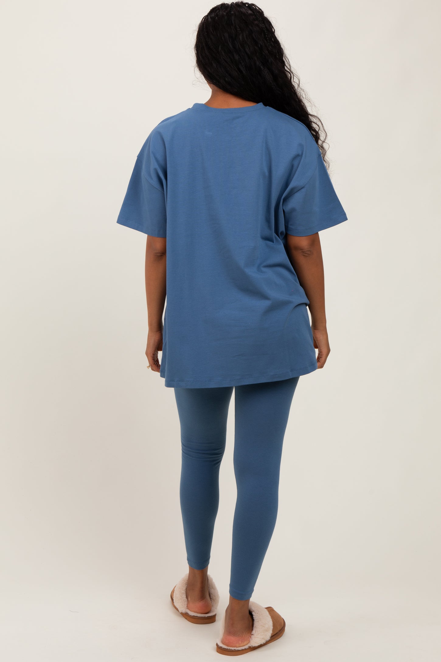 woman wearing a relaxed fit blue t-shirt and matching blue leggings, standing with her back to the camera