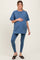 woman wearing a blue maternity t-shirt and matching leggings, gently holding her baby bump